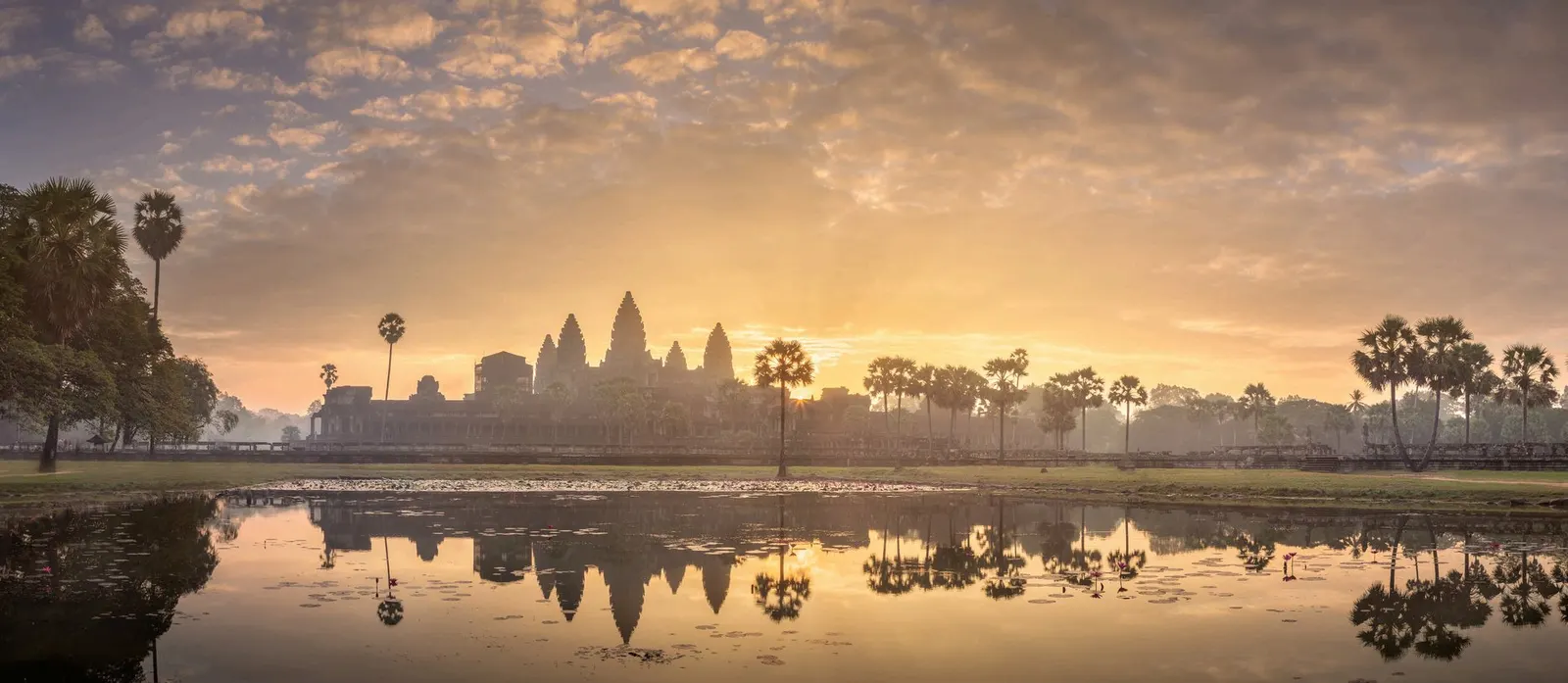 Las torres de Angkor Wat recortadas contra el cielo del amanecer y reflejadas en el estanque que hay frente al templo.