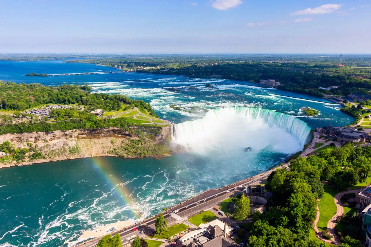 Las cataratas del Niágara vistas desde el aire, con la herradura de agua cayendo y un arcoíris sobre la espuma del río.