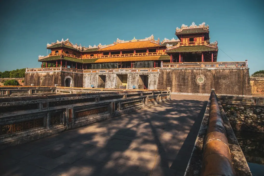 La puerta Ngo Mon de la Ciudadela Imperial de Hue, con su pabellón de tejados curvos amarillos sobre el muro de piedra y el puente de acceso en primer plano.