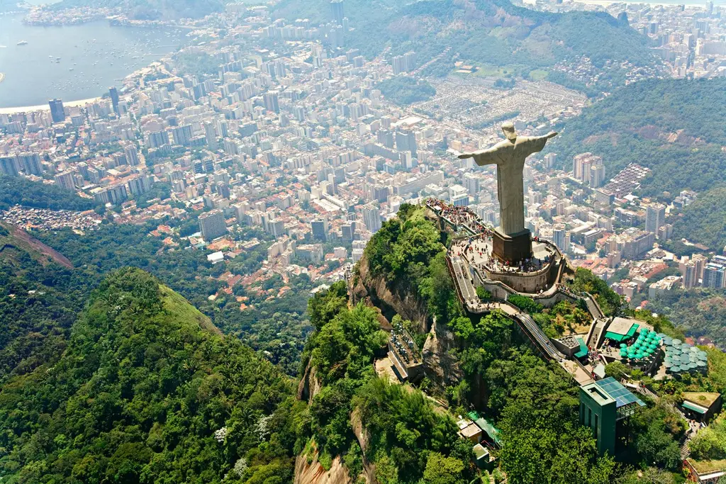 El Cristo Redentor sobre el cerro del Corcovado visto desde el aire, con la selva de Tijuca alrededor y los barrios de Río al fondo.